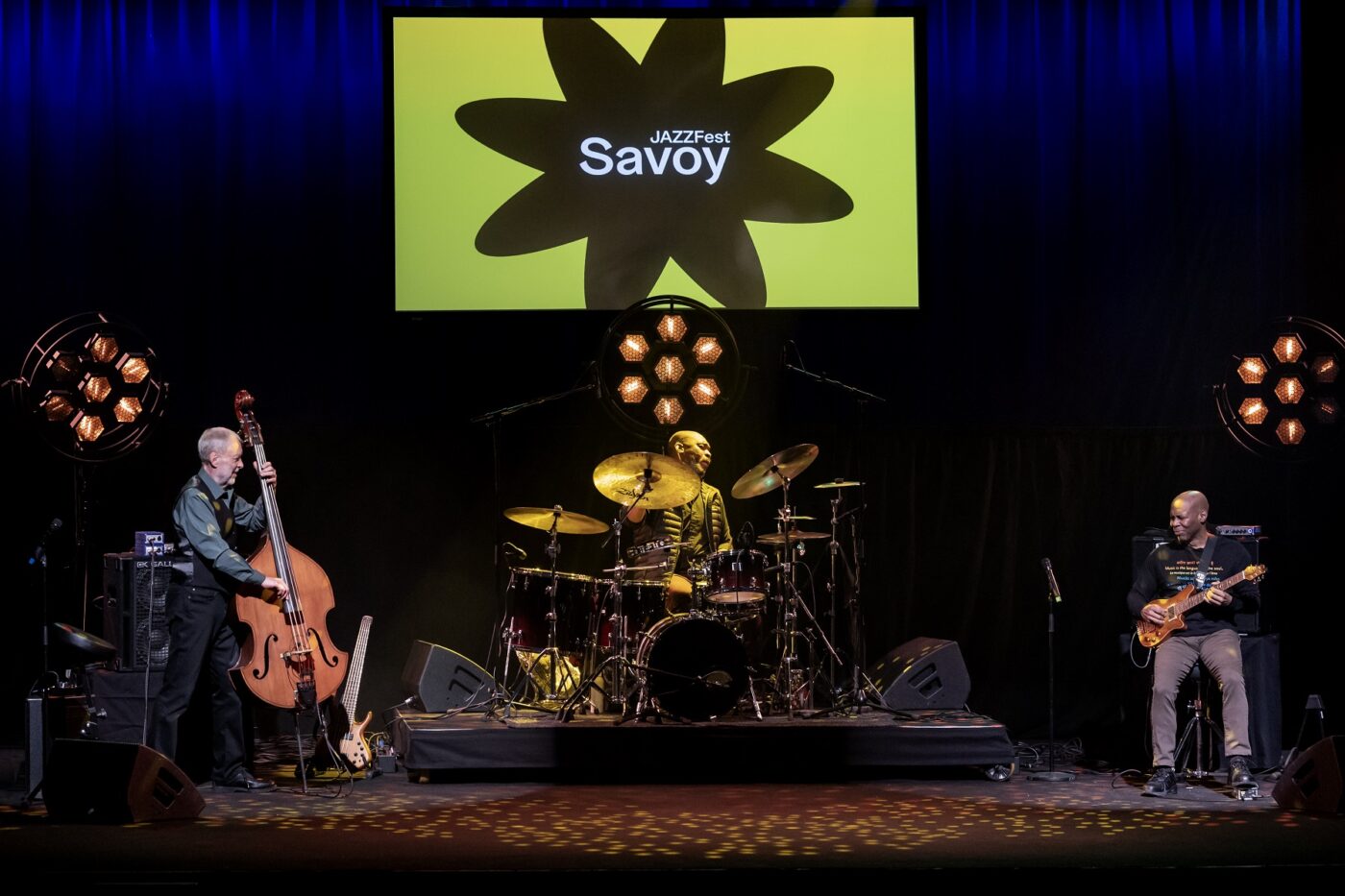 Basisti Dave Holland, rumpali Eric Harland ja kitaristi Kevin Eubanks soittavat Savoyn lavalla.